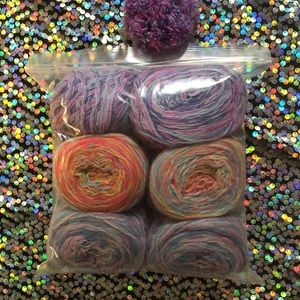 Six balls of yarn and six matching pom-poms
